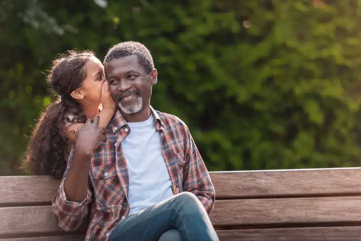 A grandfather enjoys time with his granddaughter in the park